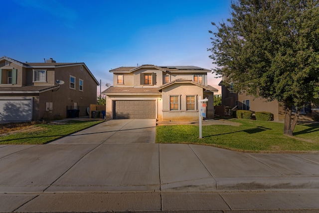 traditional-style house with stucco siding, driveway, a yard, an attached garage, and solar panels