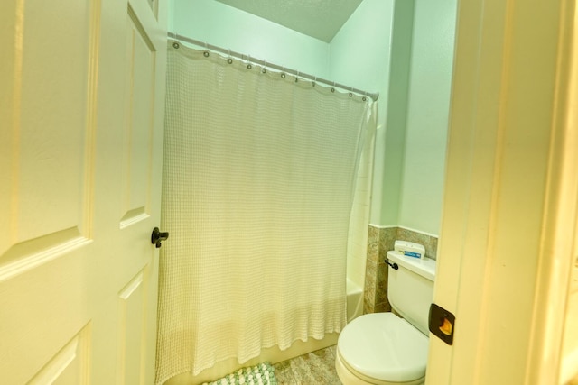 full bathroom featuring toilet, tile patterned floors, and shower / tub combo with curtain