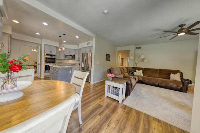 living room with visible vents, a textured ceiling, light wood-style flooring, and recessed lighting