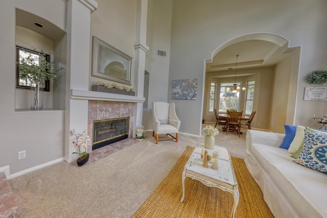 carpeted living area with baseboards, a wealth of natural light, a fireplace, and visible vents