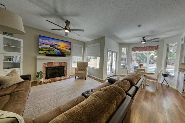 living room with dark wood-style flooring, a ceiling fan, baseboards, and plenty of natural light
