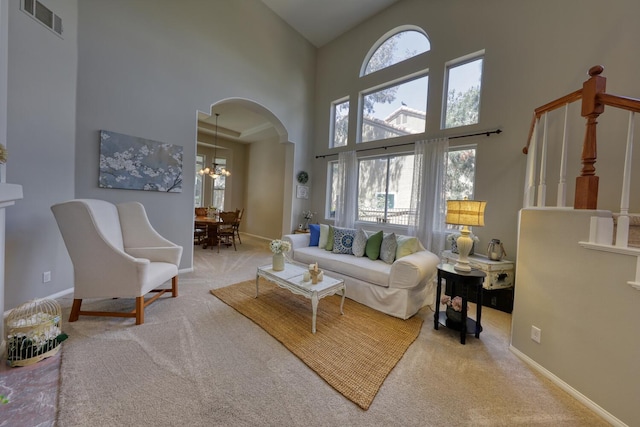 living room featuring visible vents, carpet flooring, plenty of natural light, and a high ceiling