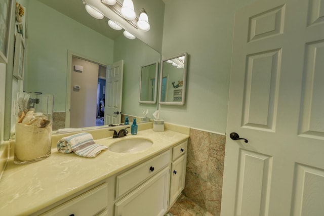 bathroom featuring vanity, wainscoting, and tile walls