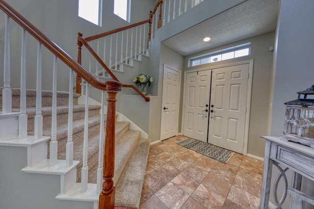 entryway with baseboards, stone finish flooring, and stairway