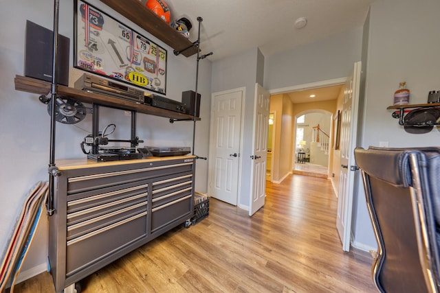 interior space with arched walkways, baseboards, and light wood-type flooring