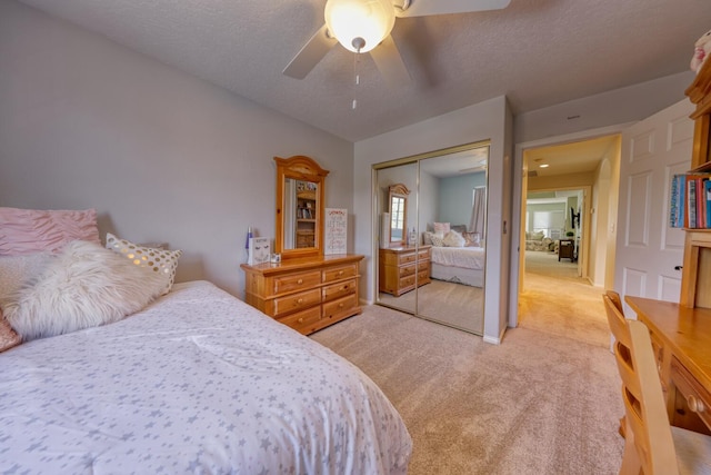 bedroom with a ceiling fan, a closet, a textured ceiling, and light colored carpet