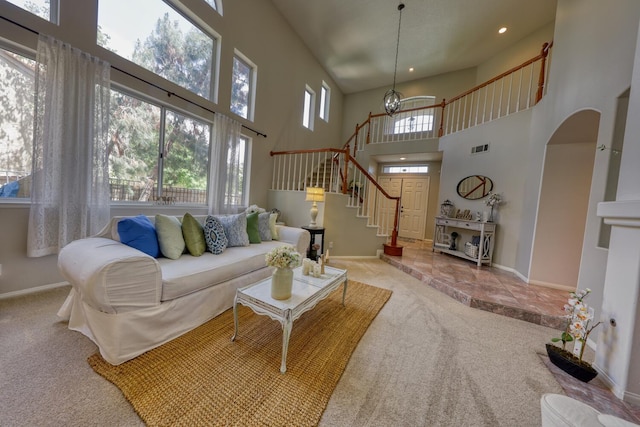 living area featuring a high ceiling, visible vents, baseboards, and carpet