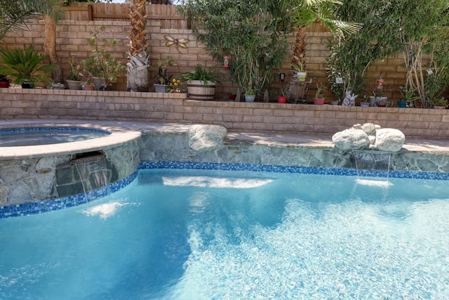 outdoor pool with fence and an in ground hot tub