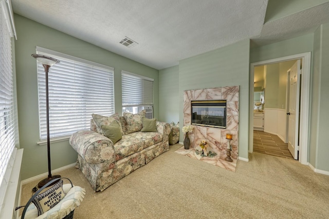 living area with visible vents, a textured ceiling, baseboards, and carpet floors