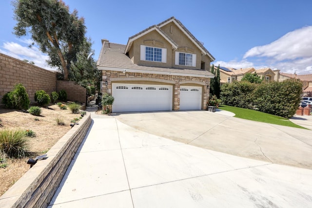 traditional-style house featuring a tile roof, stone siding, a garage, stucco siding, and concrete driveway