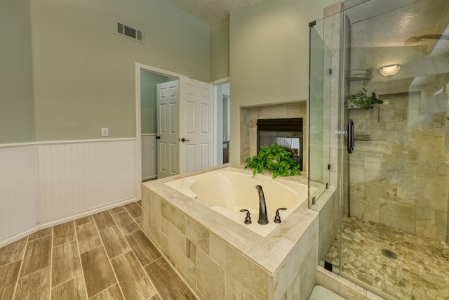 bathroom featuring visible vents, a shower stall, a bath, and a wainscoted wall