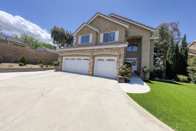 view of front facade with a front yard, concrete driveway, an attached garage, stone siding, and stucco siding
