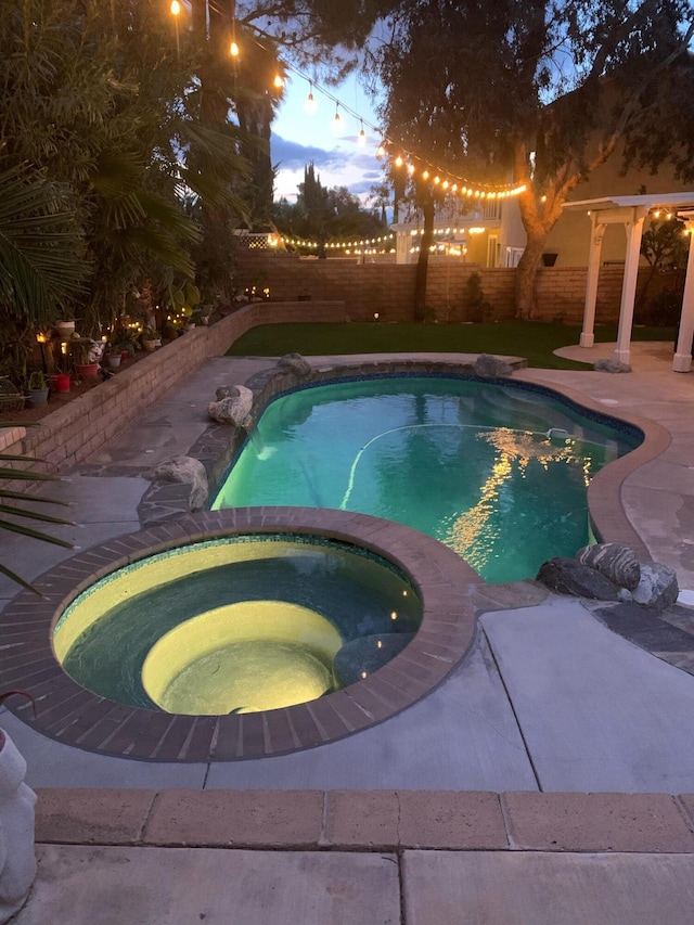 pool at dusk featuring a fenced in pool, an in ground hot tub, a fenced backyard, and a patio area