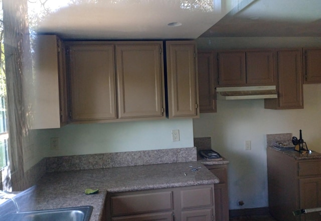 kitchen with light countertops and under cabinet range hood