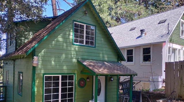 exterior space featuring roof with shingles and fence