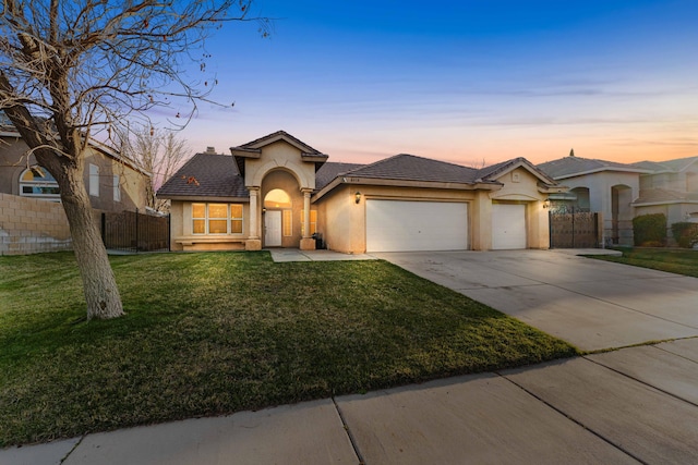 view of front of house featuring fence, stucco siding, driveway, a yard, and an attached garage