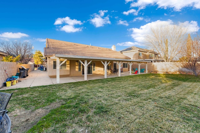 rear view of house featuring a fenced backyard, a lawn, a patio, and stucco siding