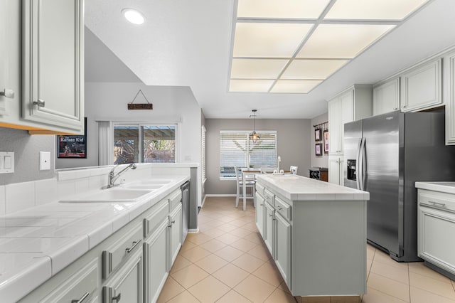 kitchen with tile countertops, stainless steel appliances, a kitchen island, and light tile patterned flooring