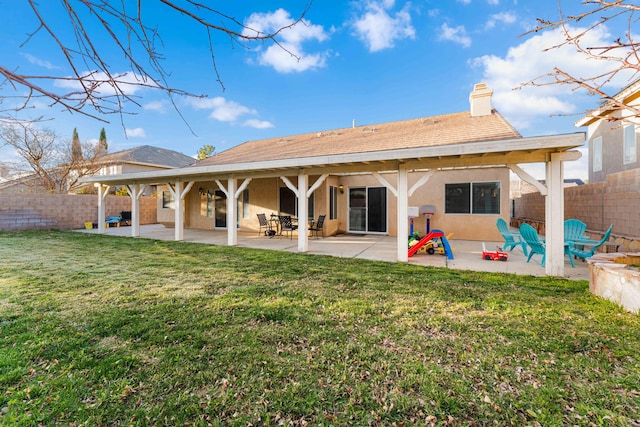 back of property featuring a yard, a fenced backyard, stucco siding, and a patio