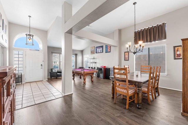 dining area with billiards, wood finished floors, an inviting chandelier, baseboards, and a towering ceiling