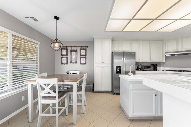 kitchen featuring white cabinets, light tile patterned floors, stainless steel fridge with ice dispenser, and visible vents