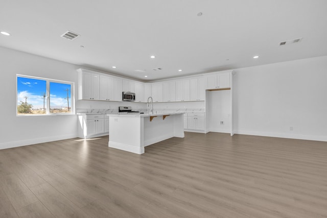 2929 W 28th St, Rosamond, CA 93560 - kitchen with stainless steel microwave, open floor plan, light wood-style flooring, white cabinetry, and recessed lighting