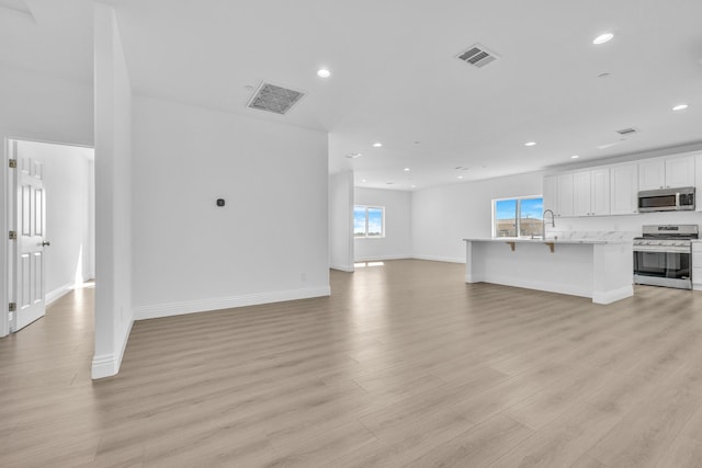 2929 W 28th St, Rosamond, CA 93560 - unfurnished living room with recessed lighting, light wood finished floors, plenty of natural light, and baseboards
