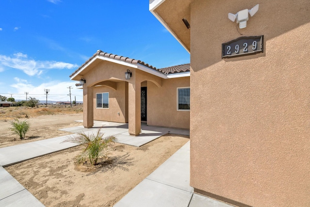 2929 W 28th St, Rosamond, CA 93560 - view of exterior entry with stucco siding, a patio, and a tiled roof