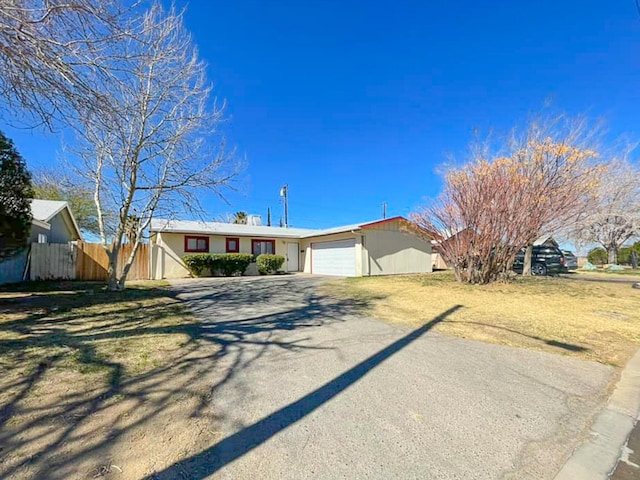 ranch-style home featuring a garage, driveway, and fence