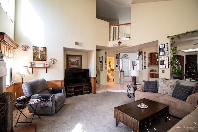 carpeted living room featuring wainscoting, visible vents, wood walls, and stairway