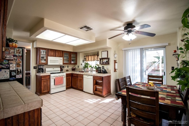 kitchen featuring glass insert cabinets, white appliances, light countertops, and visible vents