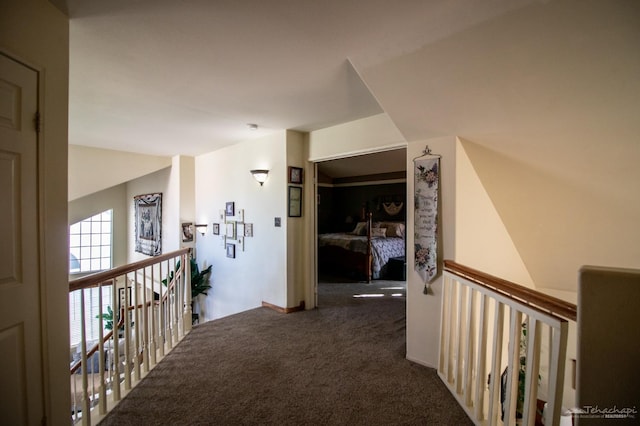 hallway with dark carpet and an upstairs landing