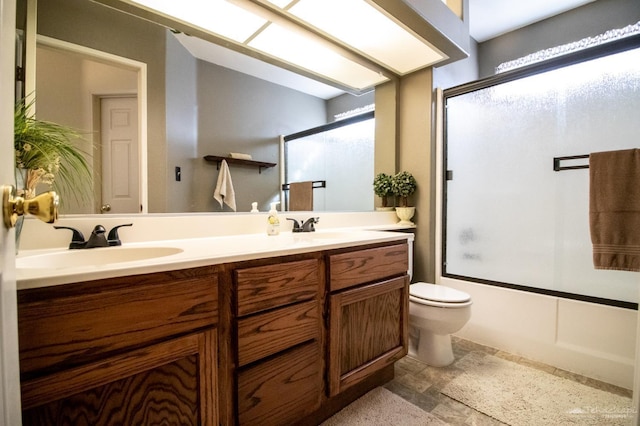 bathroom featuring double vanity, plenty of natural light, combined bath / shower with glass door, and a sink