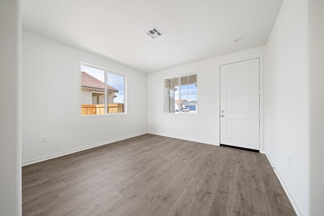 empty room featuring visible vents, baseboards, and wood finished floors