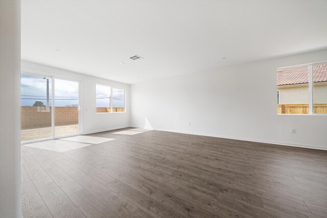spare room featuring baseboards, dark wood-style floors, and visible vents