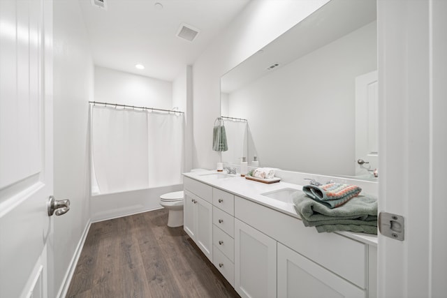 bathroom with double vanity, visible vents, wood finished floors, a sink, and toilet