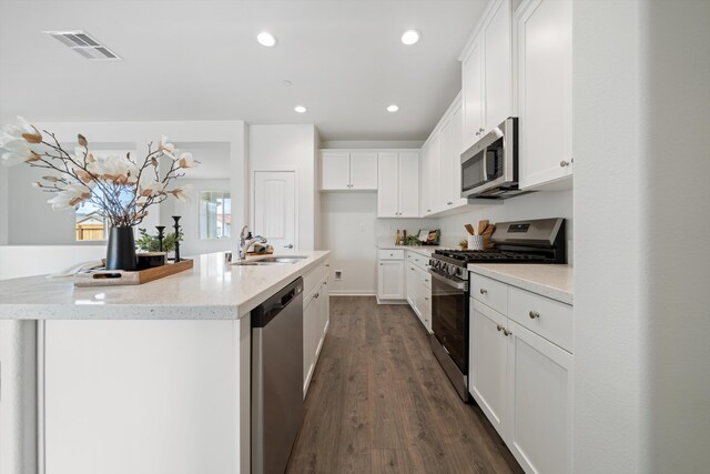 kitchen featuring visible vents, dark wood-type flooring, white cabinets, a sink, and appliances with stainless steel finishes