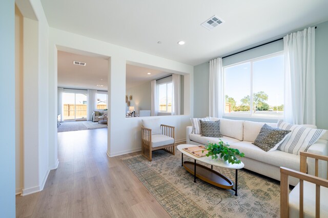 living room with light wood-style floors, plenty of natural light, recessed lighting, and visible vents