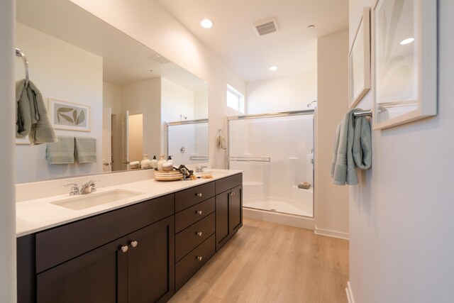 bathroom with visible vents, a sink, a stall shower, and wood finished floors