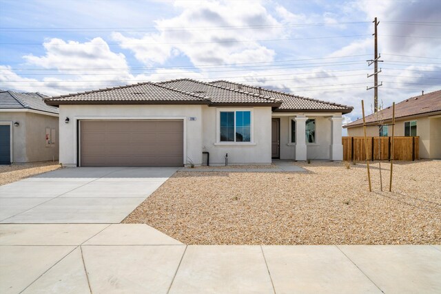 view of front of house featuring fence, a tiled roof, concrete driveway, and stucco siding