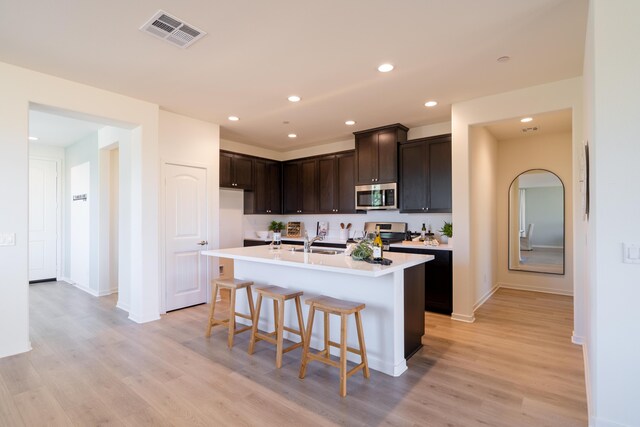 kitchen with visible vents, appliances with stainless steel finishes, light wood-type flooring, a sink, and light countertops
