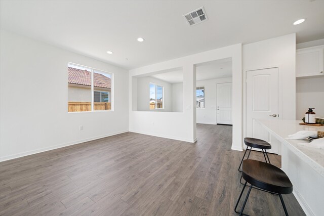unfurnished living room with recessed lighting, baseboards, visible vents, and dark wood finished floors