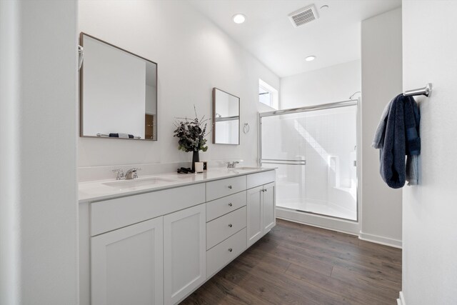 bathroom featuring a sink, a stall shower, wood finished floors, and visible vents