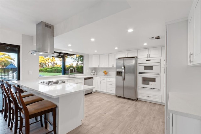 42722 W 20th St, Lancaster, CA 93534 - kitchen featuring stainless steel appliances, island range hood, a peninsula, a sink, and white cabinets