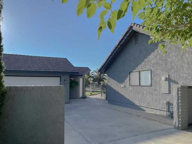 42722 W 20th St, Lancaster, CA 93534 - view of side of property with stucco siding, a garage, a gate, and driveway
