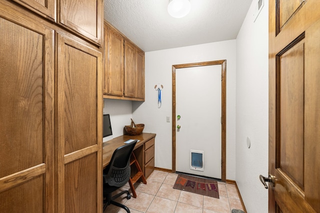 office area with built in desk, light tile patterned floors, visible vents, a textured ceiling, and baseboards