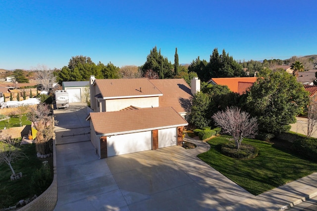 view of front facade featuring a garage, a chimney, driveway, and a tiled roof