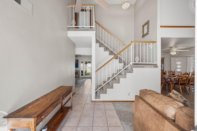 entrance foyer featuring baseboards, visible vents, tile patterned flooring, stairs, and a high ceiling