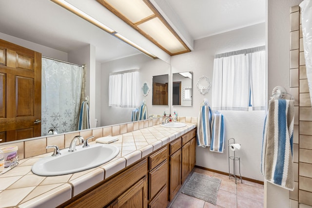 full bath with tile patterned flooring, a sink, baseboards, and double vanity