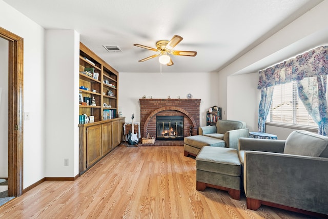 sitting room with light wood-style floors, baseboards, a brick fireplace, and visible vents